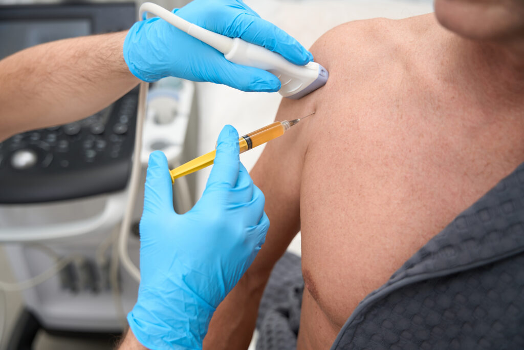 Medical specialist performing biopsy sampling from patient shoulder